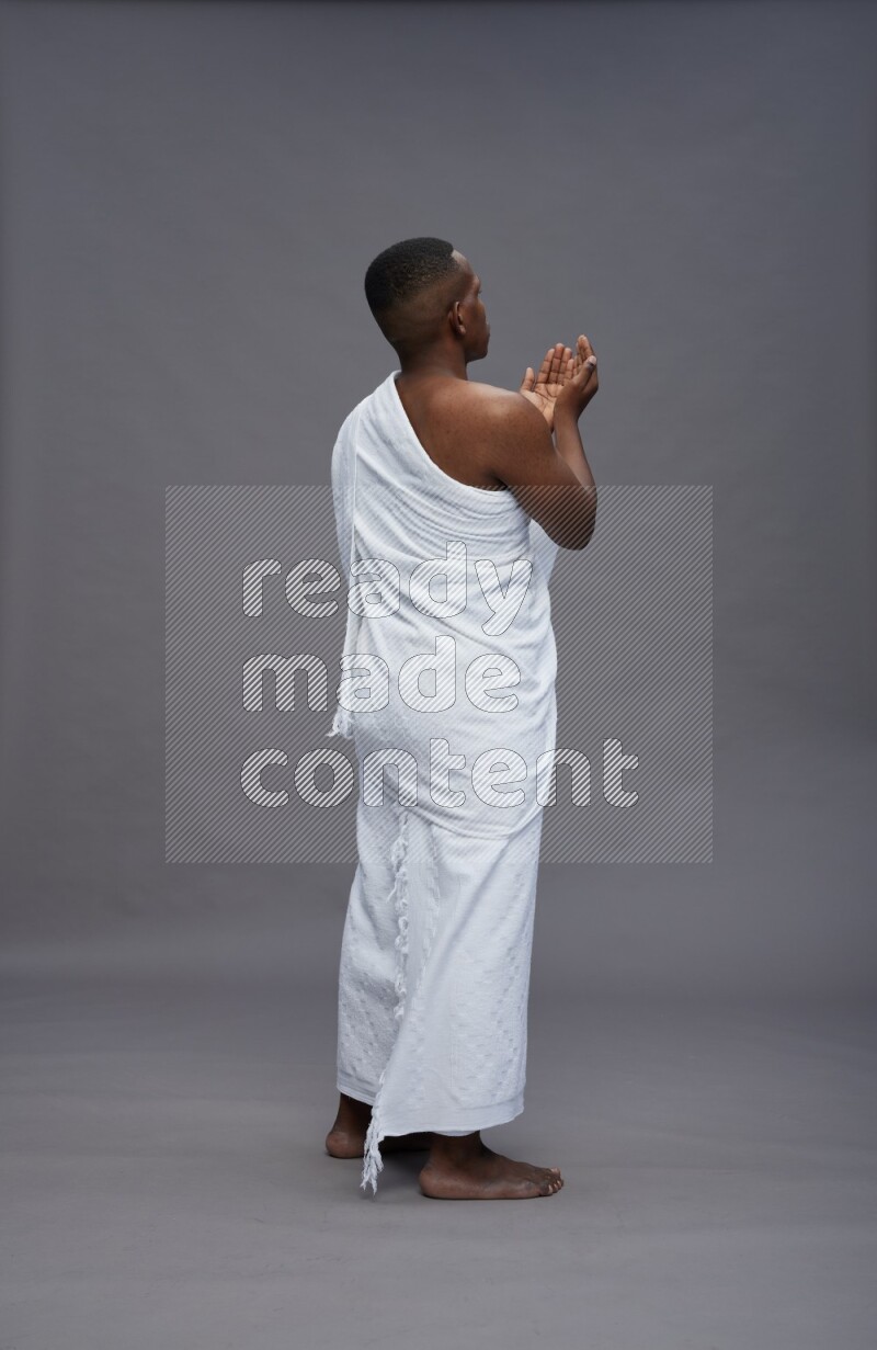 A man wearing Ehram Standing dua'a on gray background