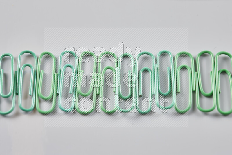 Green paper clips isolated on a grey background