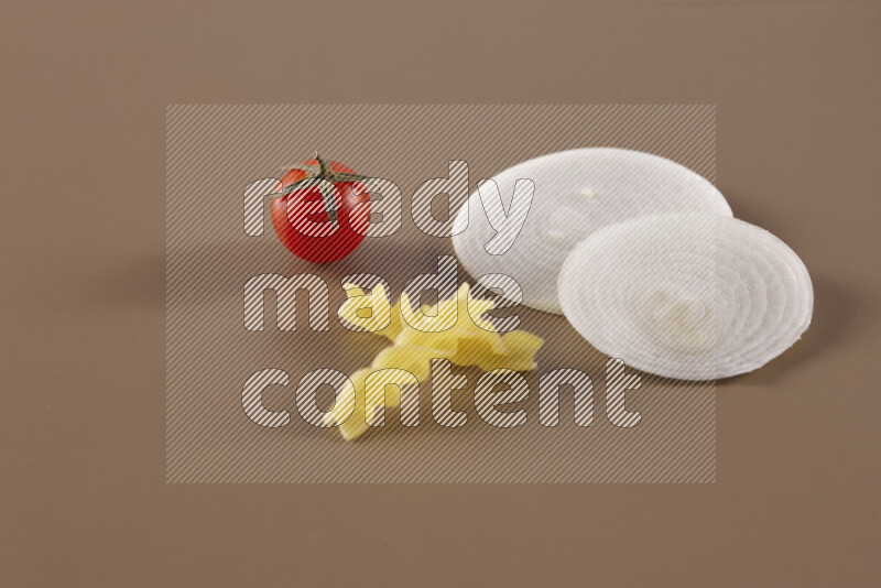 Raw pasta with different ingredients such as cherry tomatoes, garlic, onions, red chilis, black pepper, white pepper, bay laurel leaves, rosemary and cardamom on beige background