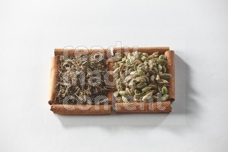 2 squares of cinnamon sticks full of cardamom and dried basil on white flooring