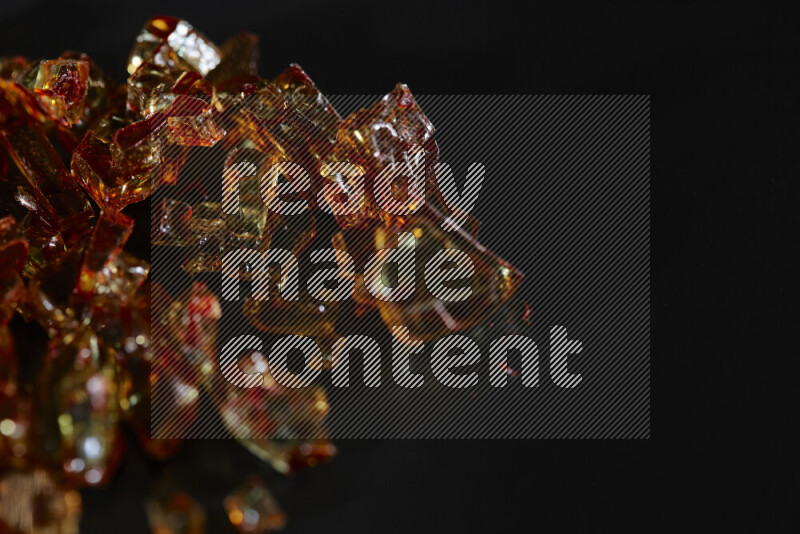 Transparent orange fragments of glass scattered on a black background