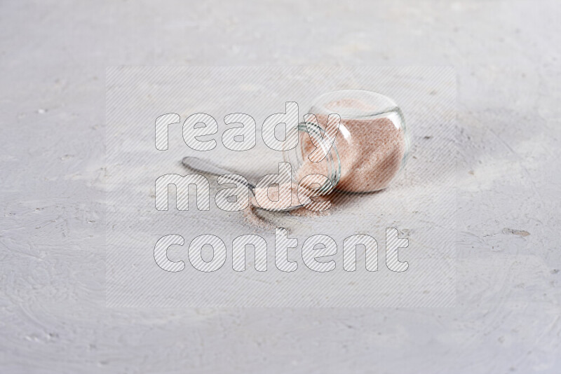 A glass jar full of fine himalayan salt on white background