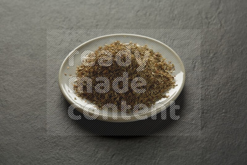 white ceramic round sauce dish filled with herbs on grey textured countertop