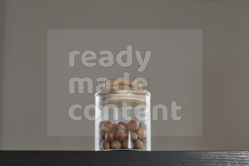 Hazelnuts in a glass jar on black background