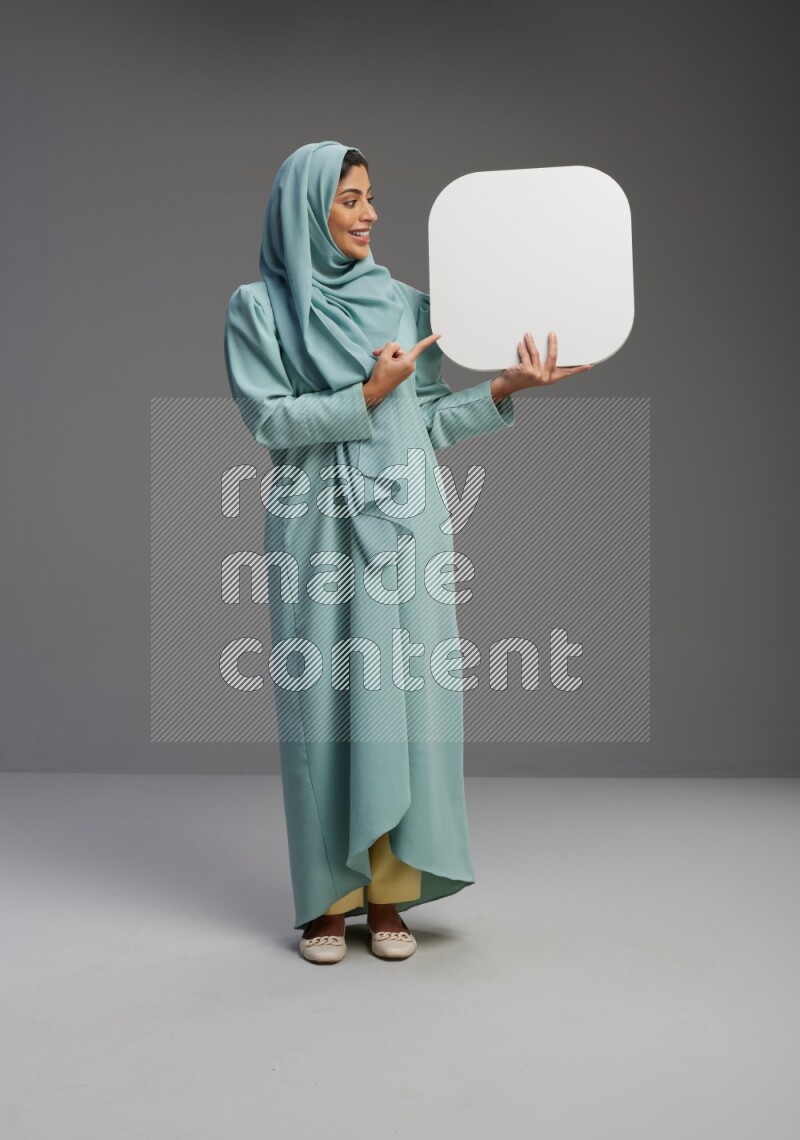 Saudi Woman wearing Abaya standing holding social media sign on Gray background