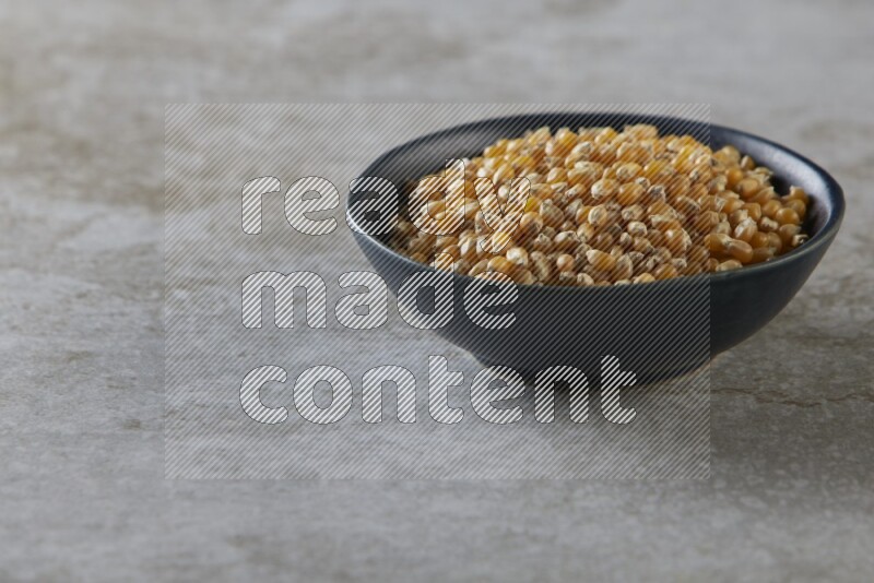 corn kernel in a black ceramic bowl on a grey textured countertop