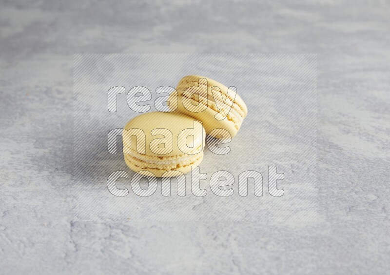 45º Shot of two Yellow Vanilla macarons  on white  marble background