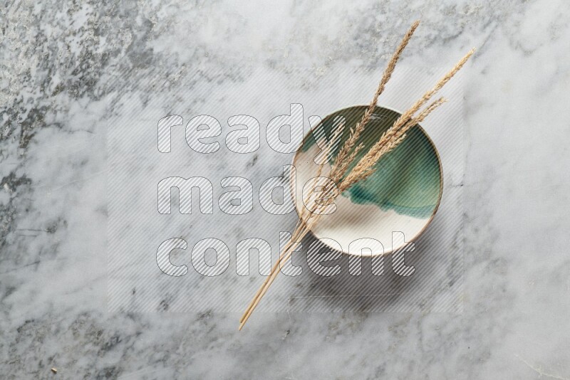 Wheat stalks on multicolored pottery plate on grey marble background