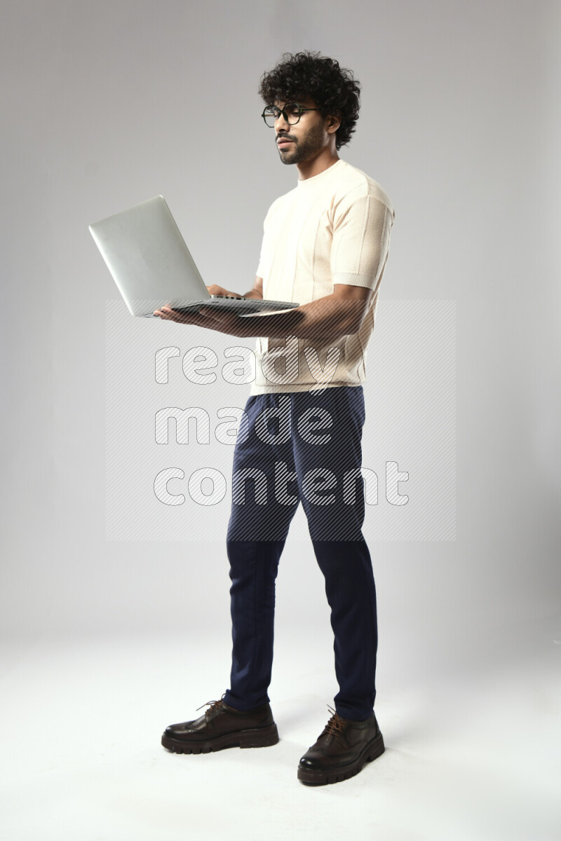A man wearing casual standing and working on a laptop on white background