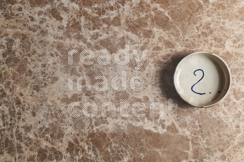 وعاء فخاري متعدد الألوان على خلفية من الرخام البيج