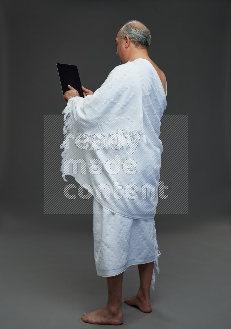 A man wearing Ehram Standing working on tablet on gray background