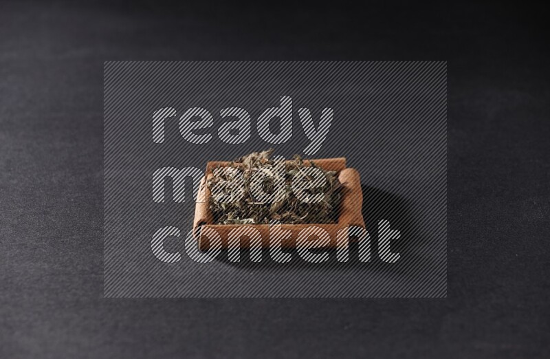 A single square of cinnamon sticks full of dried basil on black flooring