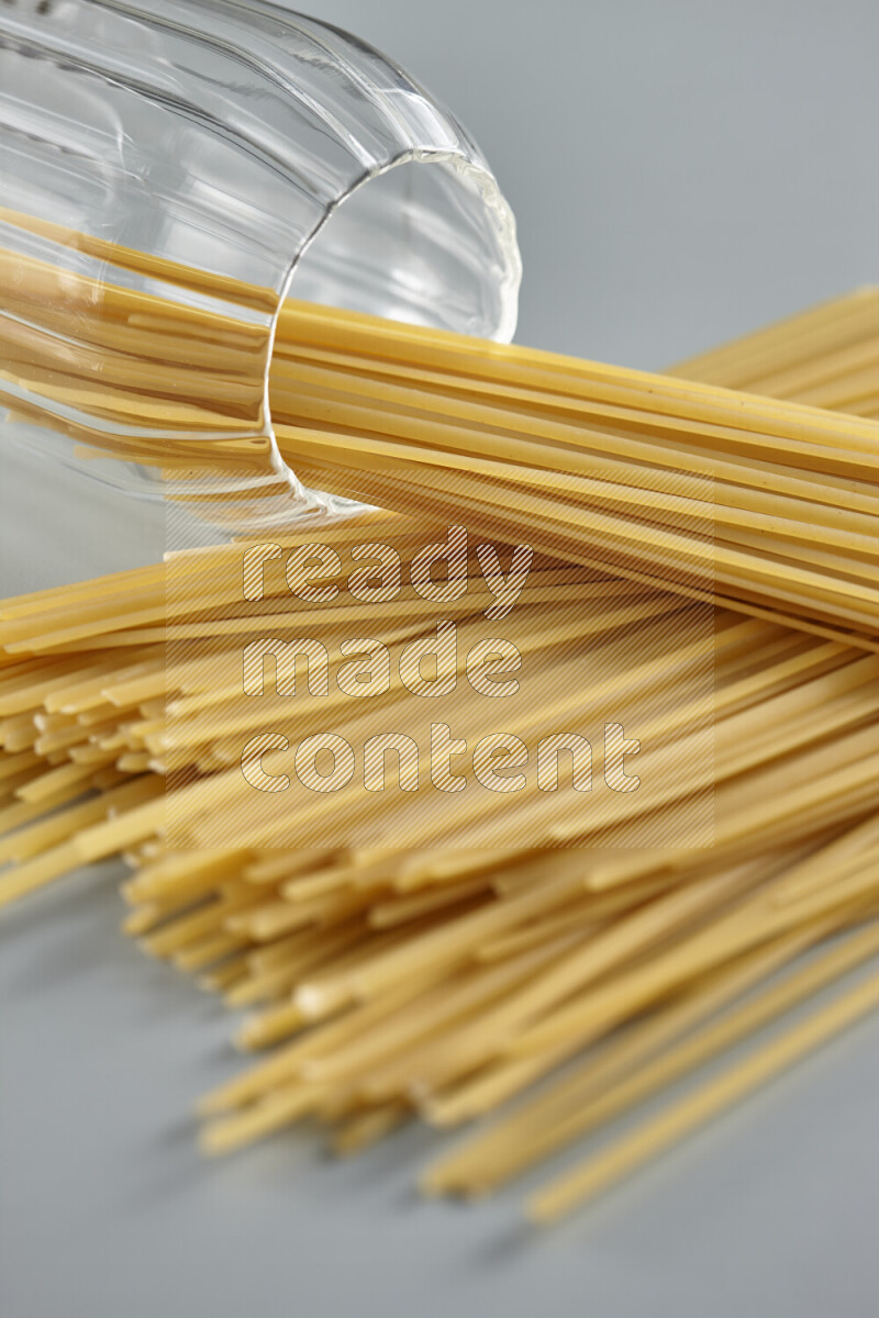 Flipped jar full of raw pasta on light blue background