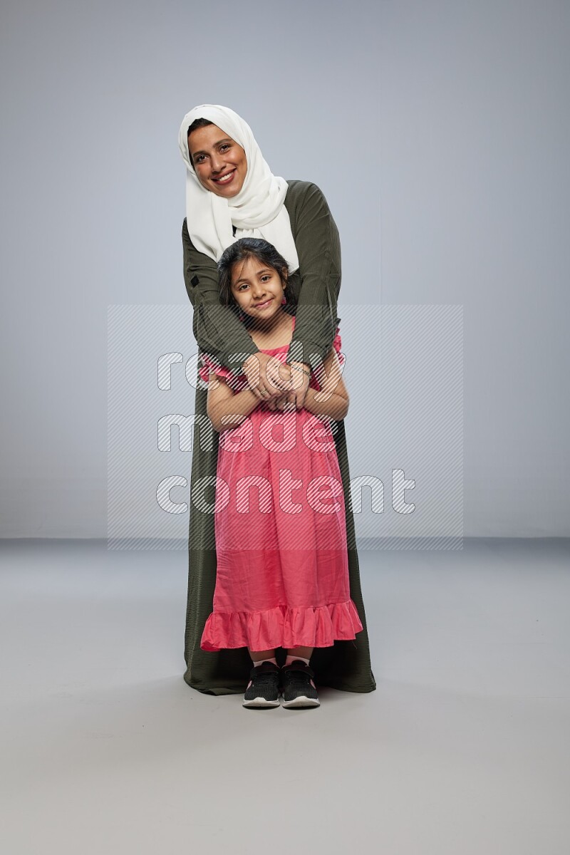 A girl and her mother interacting with the camera on gray background
