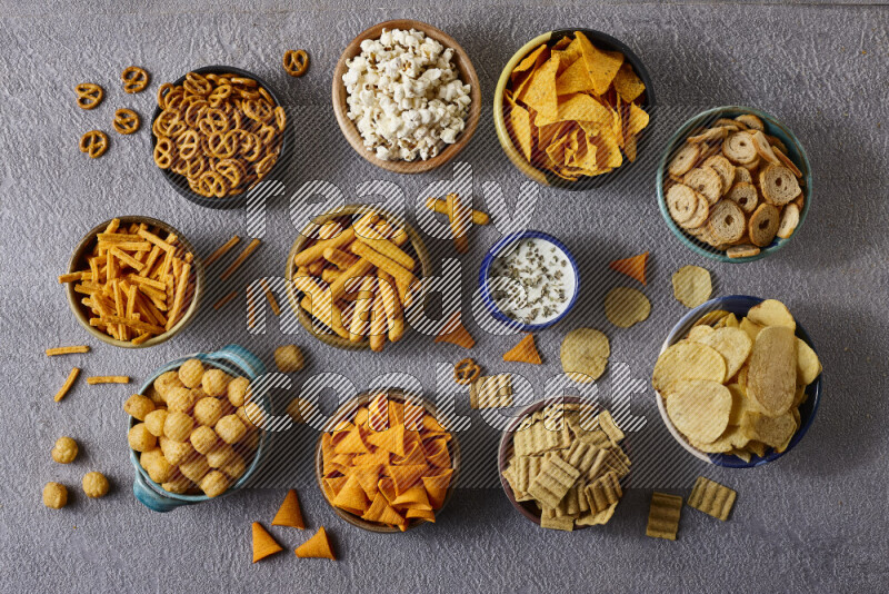 Assorted snacks in pottery bowls on grey background