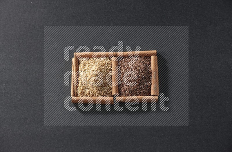 2 squares of cinnamon sticks full of flaxseeds and sesame on black flooring