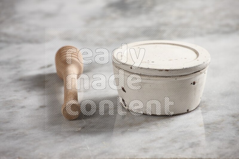 White pottery bowl with wooden honey dipper on the side on grey marble background