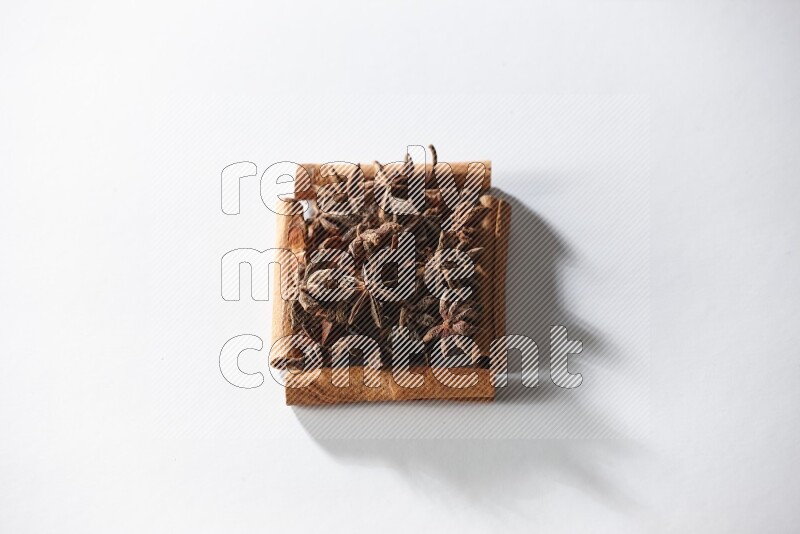 A single square of cinnamon sticks full of star anise on white flooring