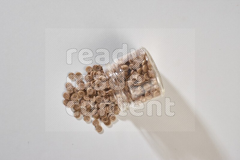 أزرار ملونة في وعاء زجاجي على خلفية رمادية