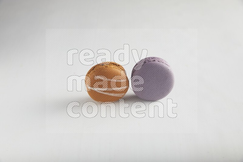 45º Shot of of two assorted Brown Irish Cream, and Purple Blueberry macarons on white background