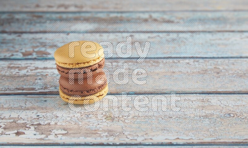 45º Shot of two Yellow and Brown Chai Latte macarons on light blue wooden background