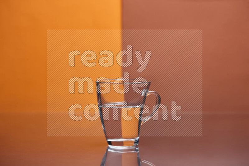 The image features a clear glassware filled with water, set against orange and dark orange background