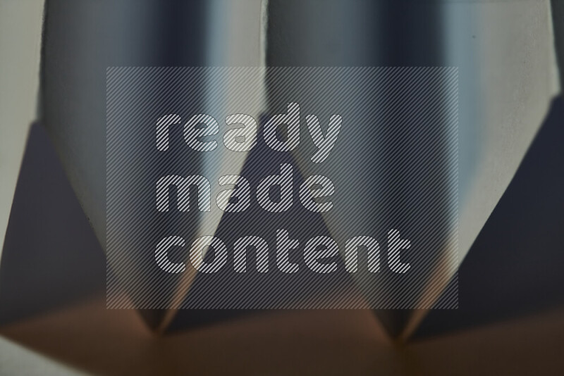 صورة مجردة مقربة تظهر طيات ورقية هندسية حادة بتدرجات اللون الأزرق مع درجات لونية دافئة