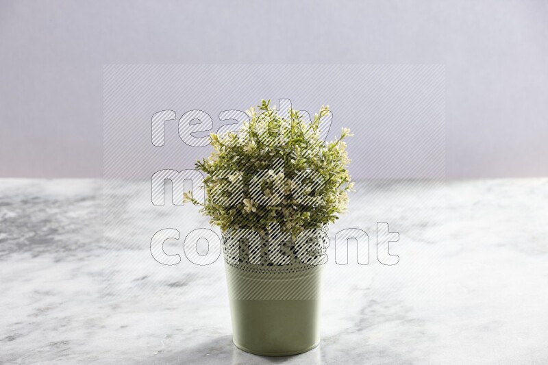 Artificial plant in green decorative pot on grey marble background