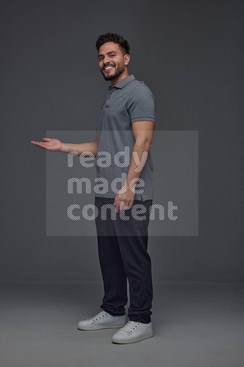 A man wearing casual standing and making multi hand gestures eye level on a gray background