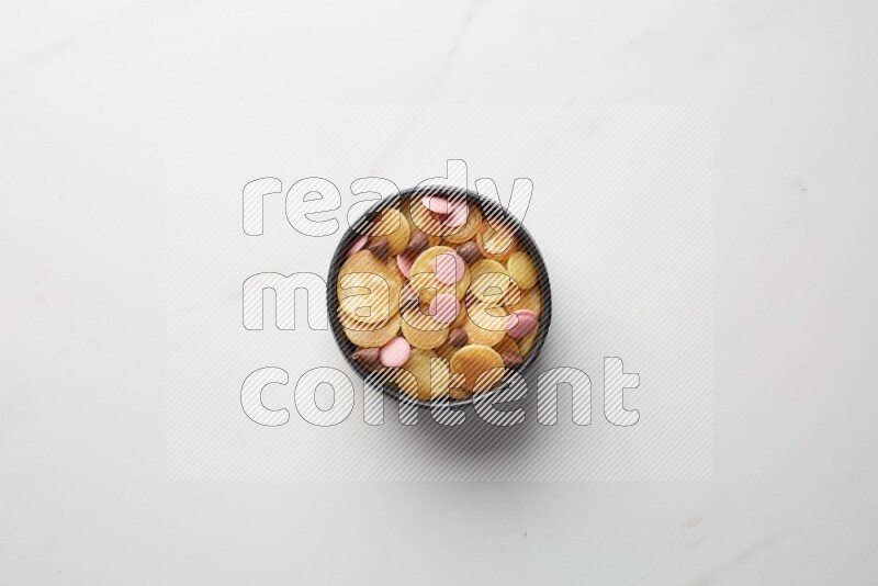 Top-view shot of mixed chocolate chips cereal pancakes in a round bowl on white background
