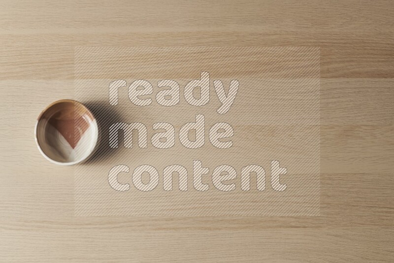 وعاء فخاري متعدد الألوان على خلفية خشبية فاتحة