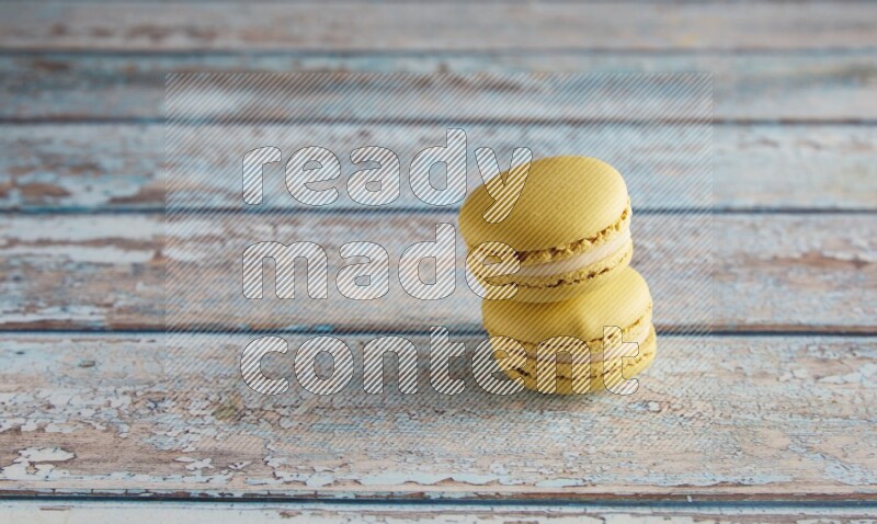 45º Shot of two Yellow Lime macarons on light blue wooden background