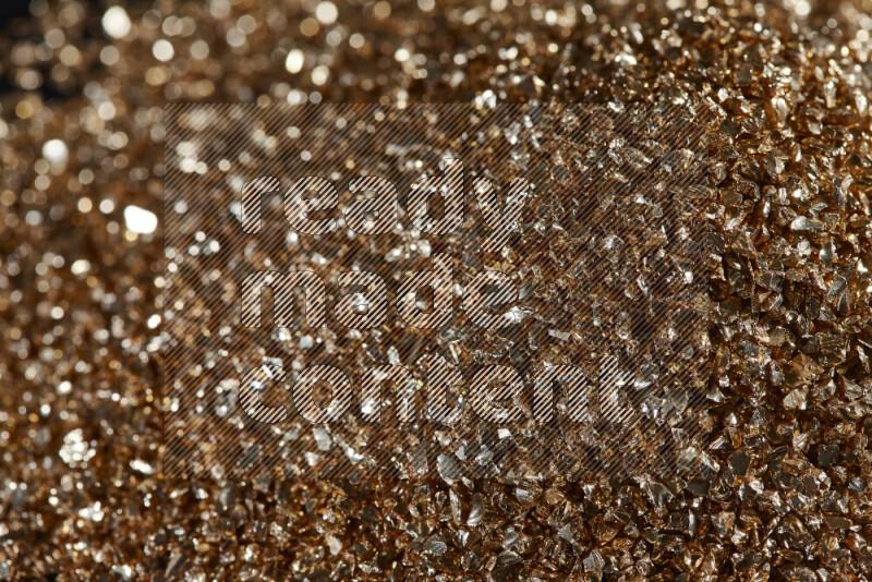 Gold shimmering fragments of glass scattered on a black background