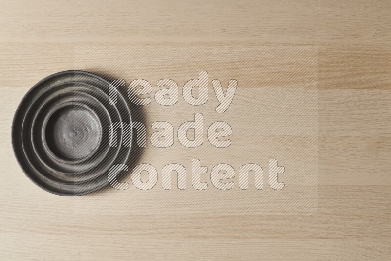 A pottery black ripple plate on light wooden background