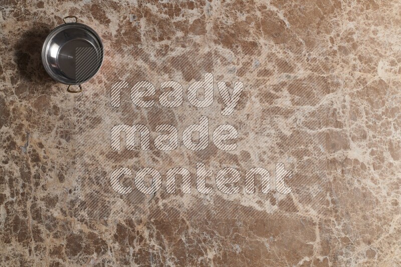 A small copper pot on beige marble background