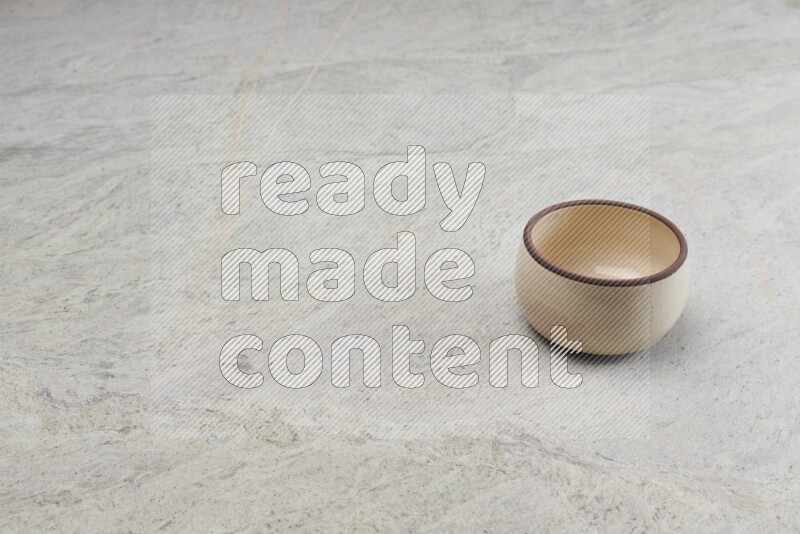 A beige pottery oven bowl on grey marble background