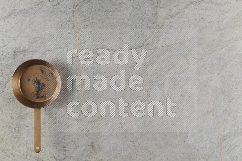 A small copper pan on grey marble background