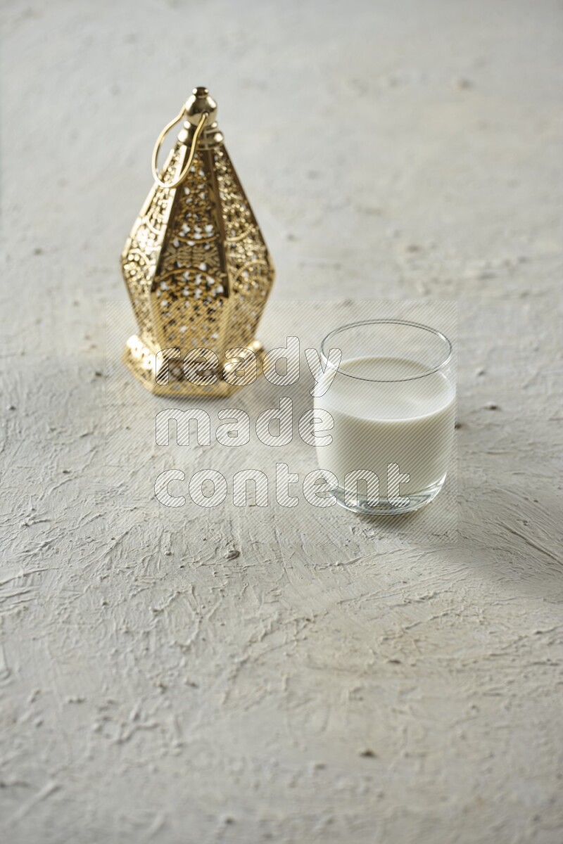 A golden lantern with different drinks, dates, nuts, prayer beads and quran on textured white background
