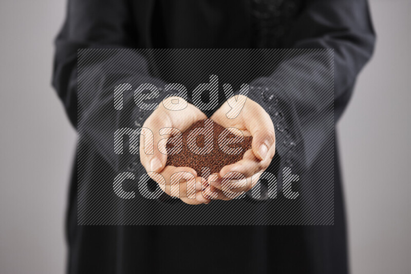 Woman in abaya holding different kinds of spices in different positions