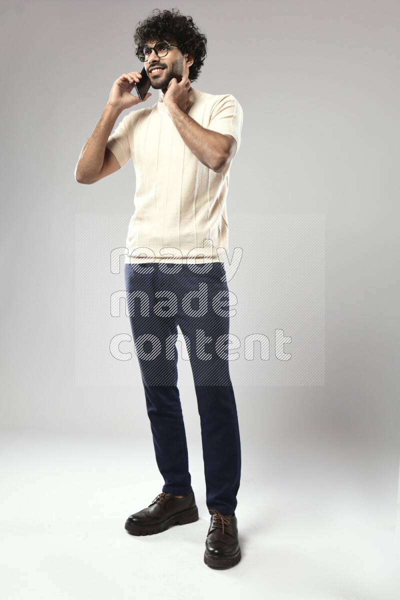 A man wearing casual standing and talking on the phone on white background