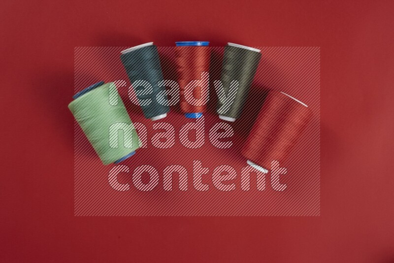 A green and red collection of sewing and tailoring tools arranged on a red background