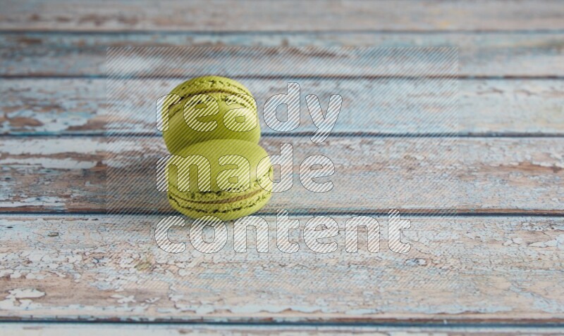 45º Shot of two Green Pistachio macarons on light blue wooden background