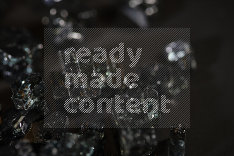 Transparent black fragments of glass scattered on a black background