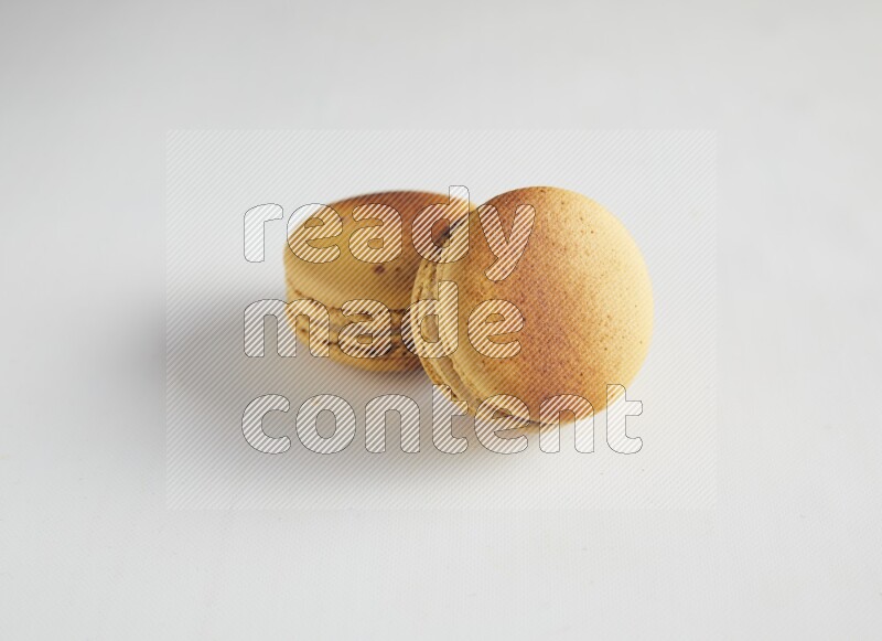 45º Shot of two Yellow Crème Brulée macarons on white background