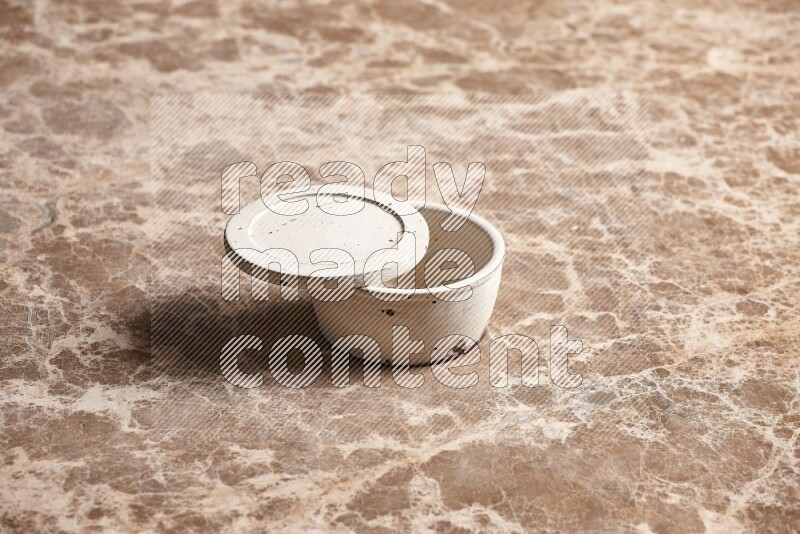 A white pottery bowl on beige marble background