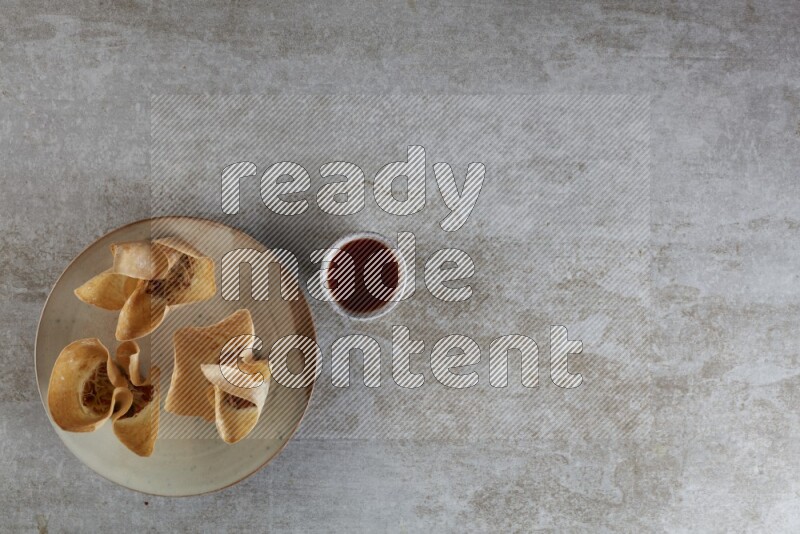 wonton cups with soy sauce ramkin on multi colored pottery on grey textured counter top