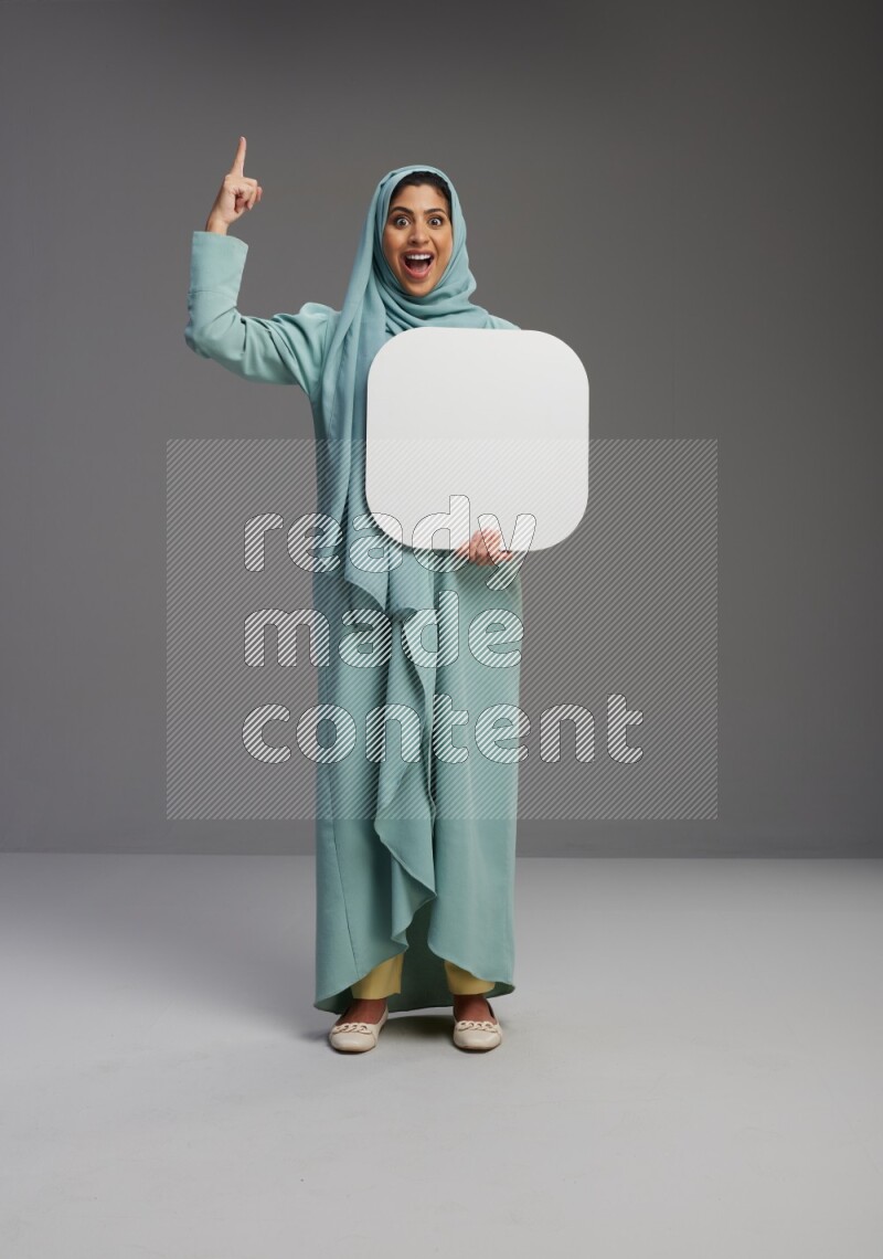 Saudi Woman wearing Abaya standing holding social media sign on Gray background