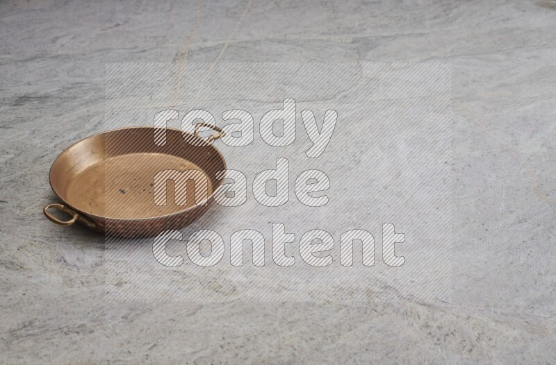 A small copper pan on grey marble background
