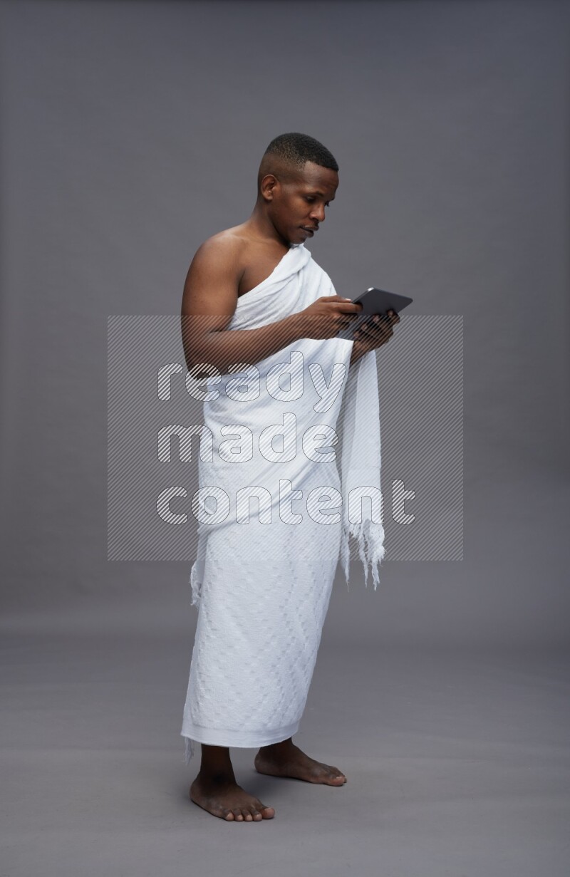 A man wearing Ehram Standing working on tablet on gray background