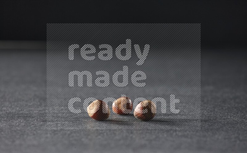3 hazelnuts on a black background in different angles